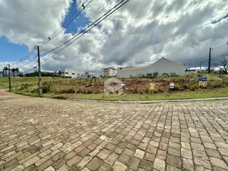 Vista externa de uma propriedade com paisagem gramada e um edifício ao fundo.