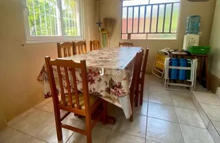 Uma mesa de jantar de madeira com tecido decorativo está no interior da sala.