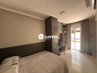 Quarto com cama e armário escuro em um apartamento com piso de madeira.