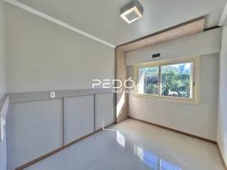 Ambiente interno com teto inclinado e janela de madeira.