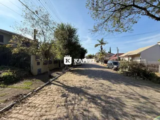 Vista externa da entrada de uma propriedade em Lajeado, Brasil, mostrando uma estrada de paralelepípedos.