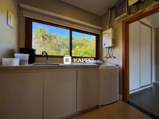 Vista da cozinha com bancada e janela de grande abertura em um imóvel em Lajeado.