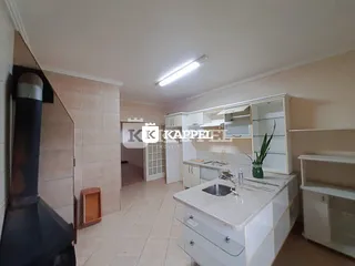 Foto de uma cozinha com armários brancos e piso claro em um imóvel.
