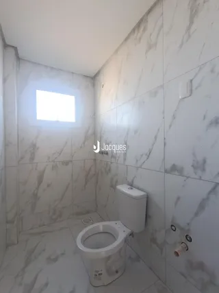 Banheiro com revestimento de azulejos brancos e detalhes em mármore.
