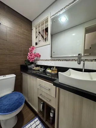 Foto de um banheiro com bancada preta e armários claros.