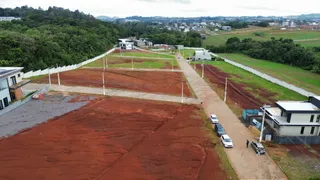 Vista aérea de um terreno grande e não construído com solo avermelhado e áreas gramadas.