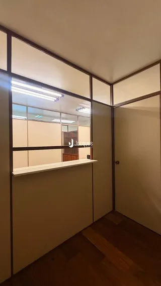 Vista interna de um corredor com piso de madeira e paredes claras.