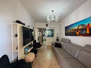 Sala de estar com sofá e televisão em um apartamento no Brasil.
