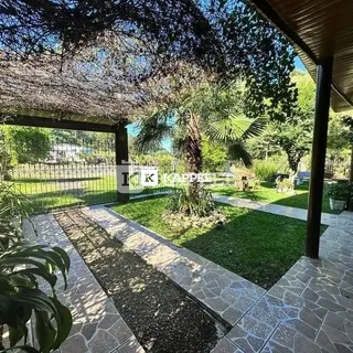 Foto da área externa com piso de pedra e gramado verde.