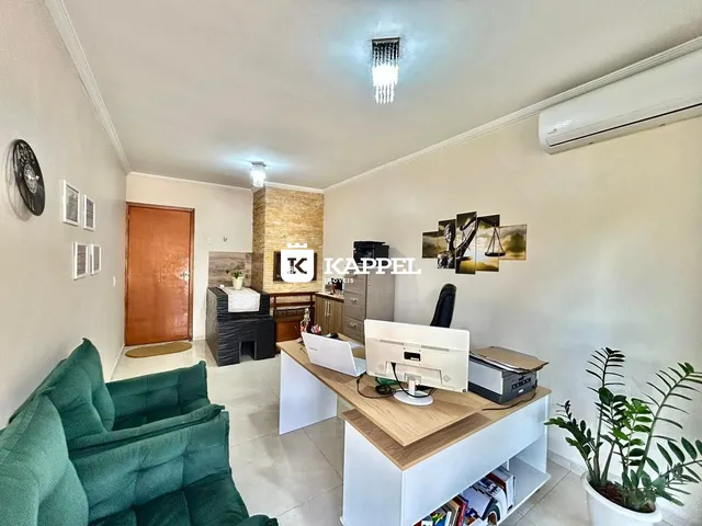 Sala de estar com sofá verde e estação de trabalho em um ambiente claro.