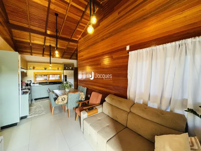 Sala de estar com revestimento de madeira e sofá claro.