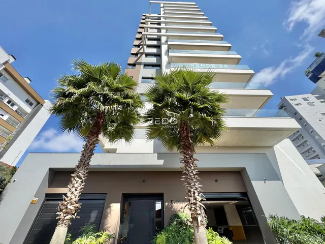 Fachada de um prédio residencial em Lajeado, Brasil com duas palmeiras em frente.
