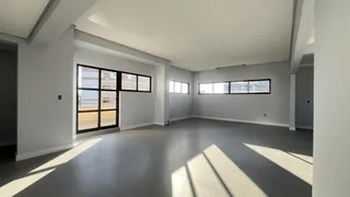 Uma sala ampla e moderna com piso de concreto e grandes janelas.
