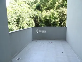 Vista de uma área externa com piso claro e parede branca.