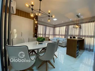 A sala de jantar apresenta uma mesa branca com cadeiras modernas e iluminação decorativa.