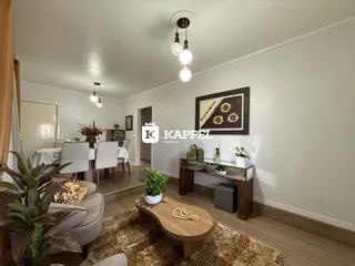 A sala de estar apresenta um sofá, mesa de centro de madeira e plantas decorativas.