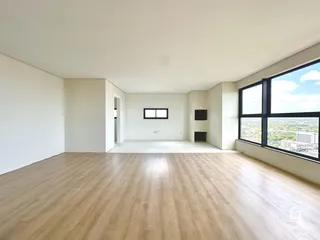 Ambiente interno amplo com piso de madeira clara e paredes brancas.