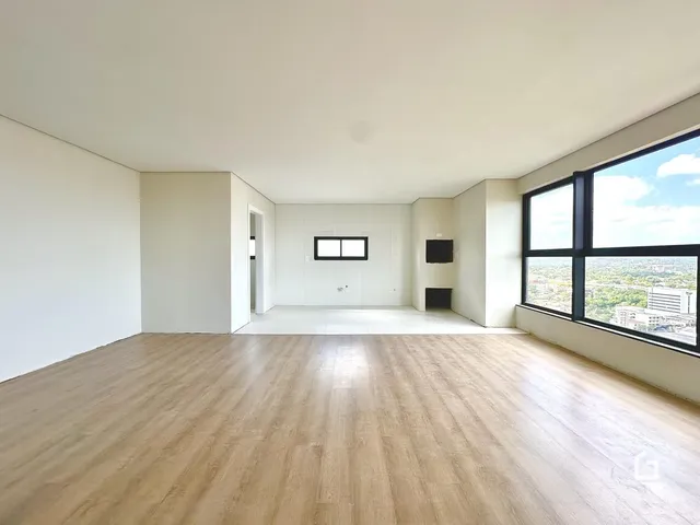 Ambiente interno amplo com piso de madeira clara e paredes brancas.