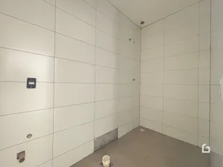 Parede interna com revestimento branco e piso de concreto.