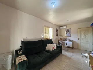 A sala de estar mostra um sofá grande e piso de madeira clara.