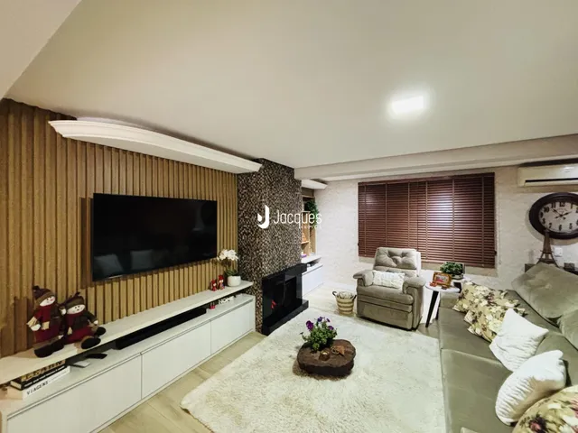 Sala de estar com sofá e televisão montada na parede em um imóvel no Brasil.