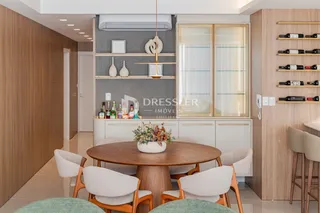 Ambiente de jantar com mesa de madeira e estantes em um interior moderno.