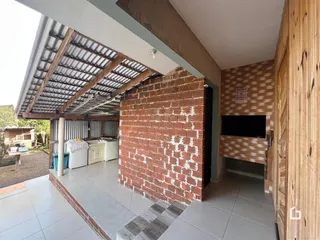 Área externa coberta com parede de tijolos aparentes e piso de cerâmica.