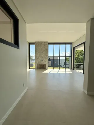 Espaço interno amplo com piso claro e grandes janelas que proporcionam muita luz natural.