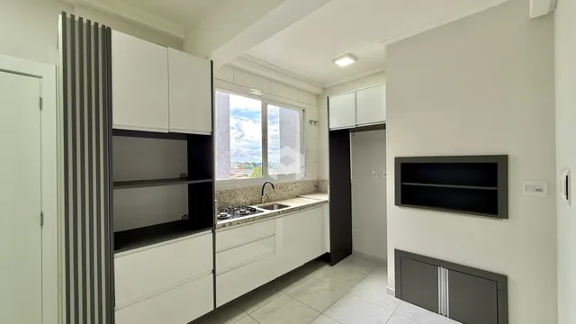 Vista interna de uma cozinha com armários brancos e bancada clara.
