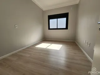 Foto de um cômodo interno com piso de madeira clara e uma janela.