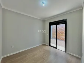Sala de estar com piso de madeira clara e porta de vidro escura.