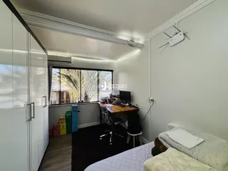 Quarto com janela de vista para a vegetação e um guarda-roupa branco na lateral esquerda.