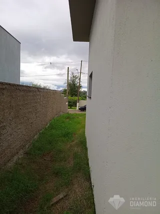 Fachada lateral de um imóvel em Lajeado, Brasil, mostrando uma parede branca e uma faixa de grama.