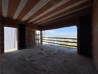 Vista interna de uma área em construção com paredes de tijolo aparente.