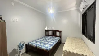 Quarto com cama de madeira e paredes brancas.