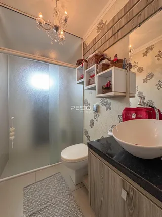 Banheiro moderno com box de vidro e bancada de madeira.