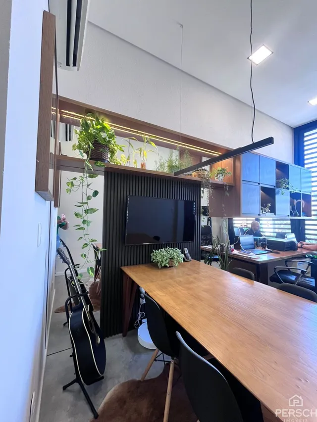 Foto de um ambiente com mesa de jantar de madeira e televisão.