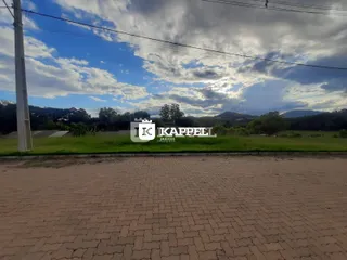 Vista panorâmica de um campo aberto com vegetação e colinas ao fundo.