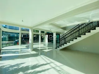 Vista de um hall amplo com escadaria e grandes janelas de vidro.