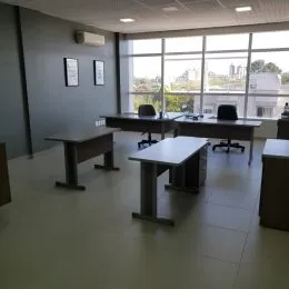 Ambiente interno com mesas longas e grandes janelas que oferecem vista.