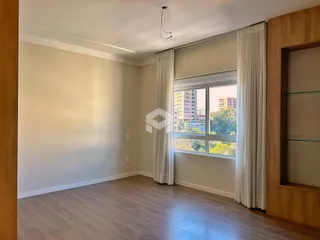 Ambiente interno de uma sala com piso de madeira clara e grande janela.