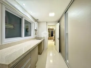 Vista de uma bancada de cozinha com armários e janelas em um imóvel no Brasil.
