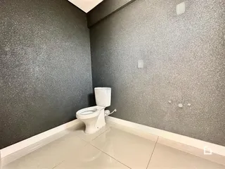 Foto de um banheiro com piso claro e vaso sanitário branco.