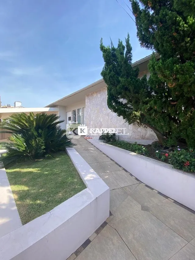 Vista externa mostrando um jardim com calçada e muro branco.