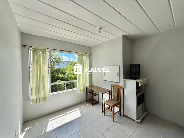 Uma sala de estar clara com janela e piso de cerâmica.