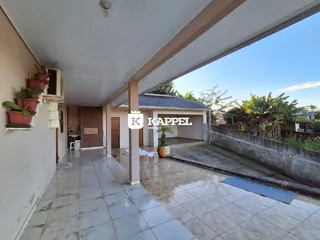 Vista da área coberta com piso de cerâmica e muro de contenção.