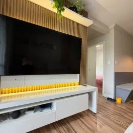 Uma sala de estar com uma televisão de tela plana montada na parede e um móvel baixo.