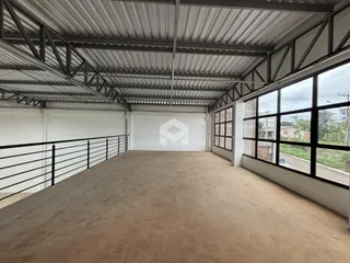 Vista interna de um espaço com teto de metal e piso de concreto.