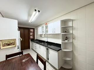 Cozinha com armários brancos e bancadas escuras em um imóvel brasileiro.