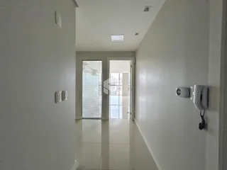 Corredor interno de uma residência com piso claro e paredes brancas.